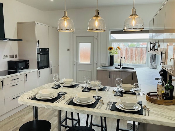 A modern kitchen with a marble countertop, black and white cabinetry, and pendant lighting.