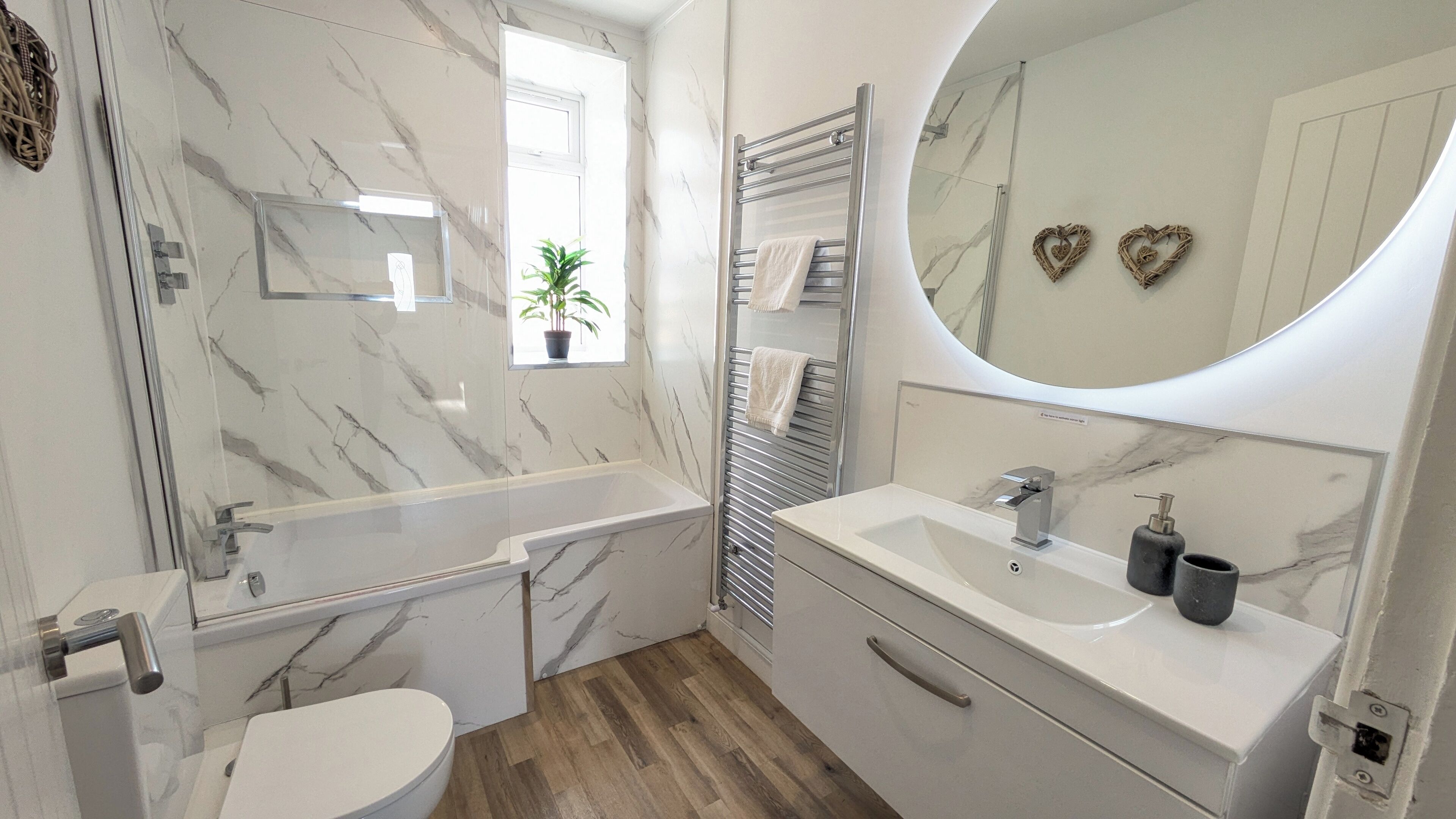 A modern bathroom with a marble vanity, a bathtub, and a toilet.