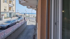 A balcony with a view of a street, parked cars, and a beach in the distance. - Mare e Conchiglie (Albenga)