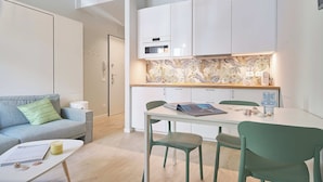 A modern kitchen with white cabinets, a built-in oven, and a backsplash with a leaf pattern. - Mare e Conchiglie (Albenga)
