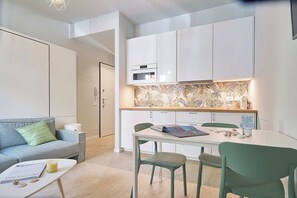 A modern kitchen with white cabinets, a built-in oven, and a backsplash with a leaf pattern. - Mare e Conchiglie (Albenga)