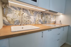 A modern kitchen with a wooden countertop, two sinks, and a decorative backsplash.