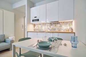 A modern kitchen with white cabinets, a built-in oven, and a backsplash with a floral pattern.