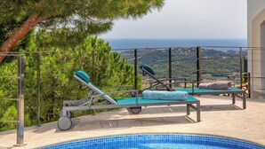 A poolside area with lounge chairs and a view of the sea. - Can Masarol: Views, Pool & BBQ - Platja d'Aro (Castell-Platja d'Aro)