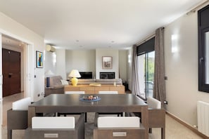 A modern living room with a sofa set, a dining table with chairs, and a TV. - Can Masarol: Views, Pool & BBQ - Platja d'Aro (Castell-Platja d'Aro)