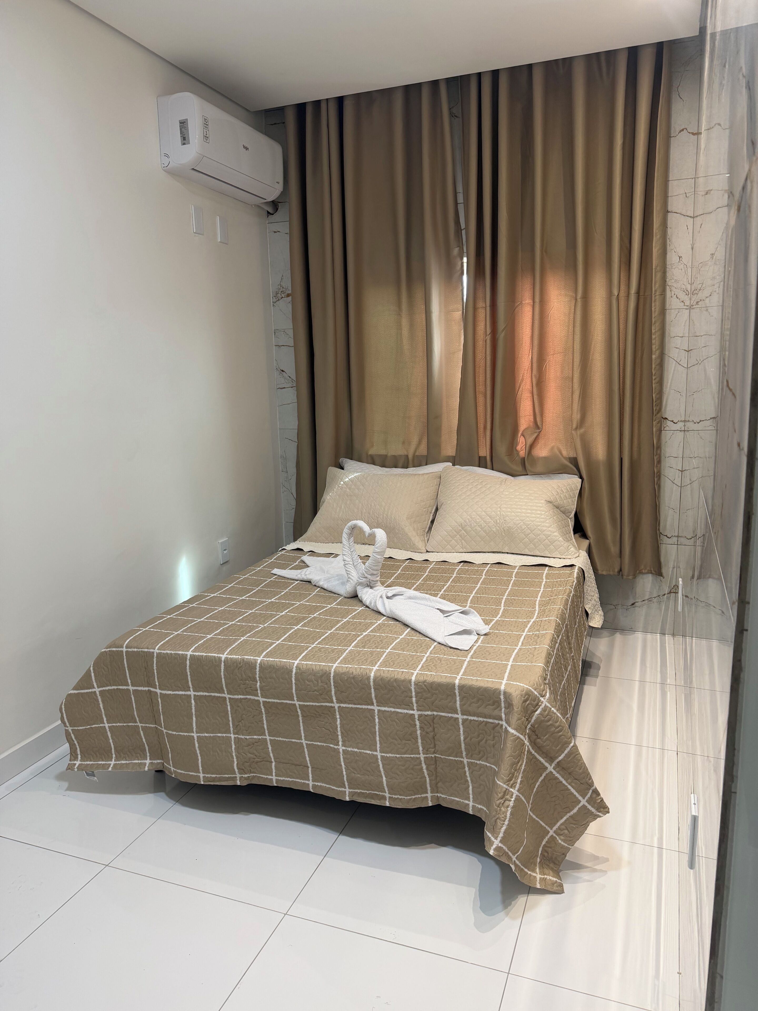 Una camera d'albergo con un letto, tende e un condizionatore.