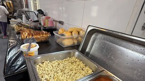 A buffet with various food items, including a large container of soup and a tray of sliced bread.