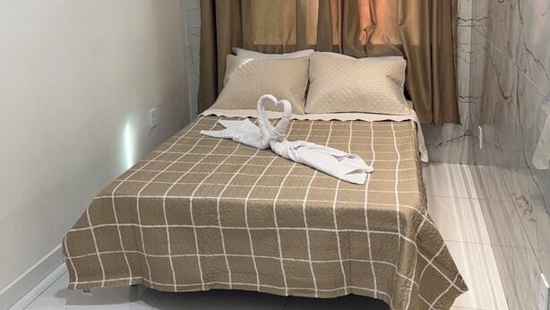 A hotel room with a bed, curtains, and an air conditioning unit.