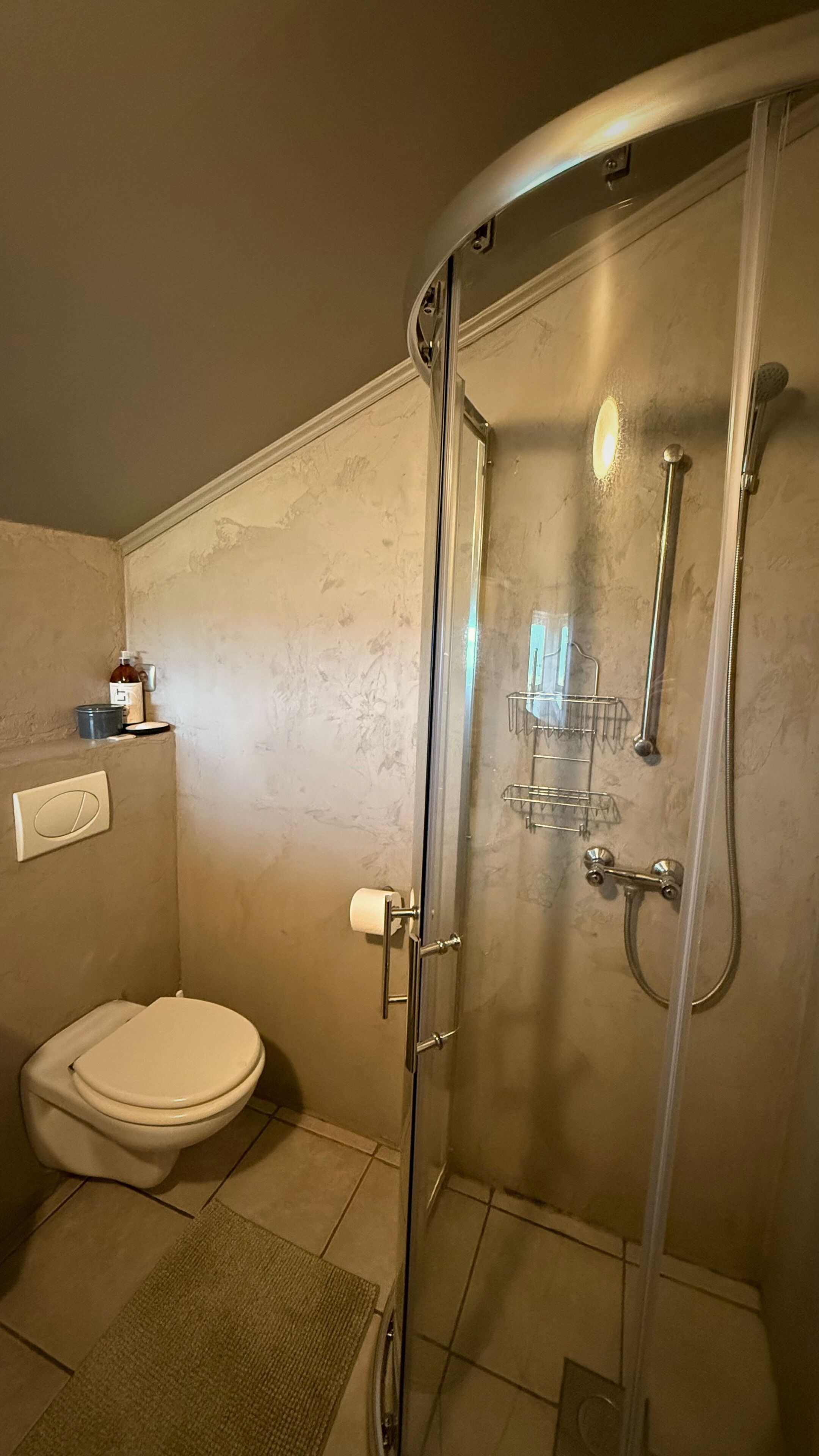 Un baño con inodoro, cabina de ducha y perchero.