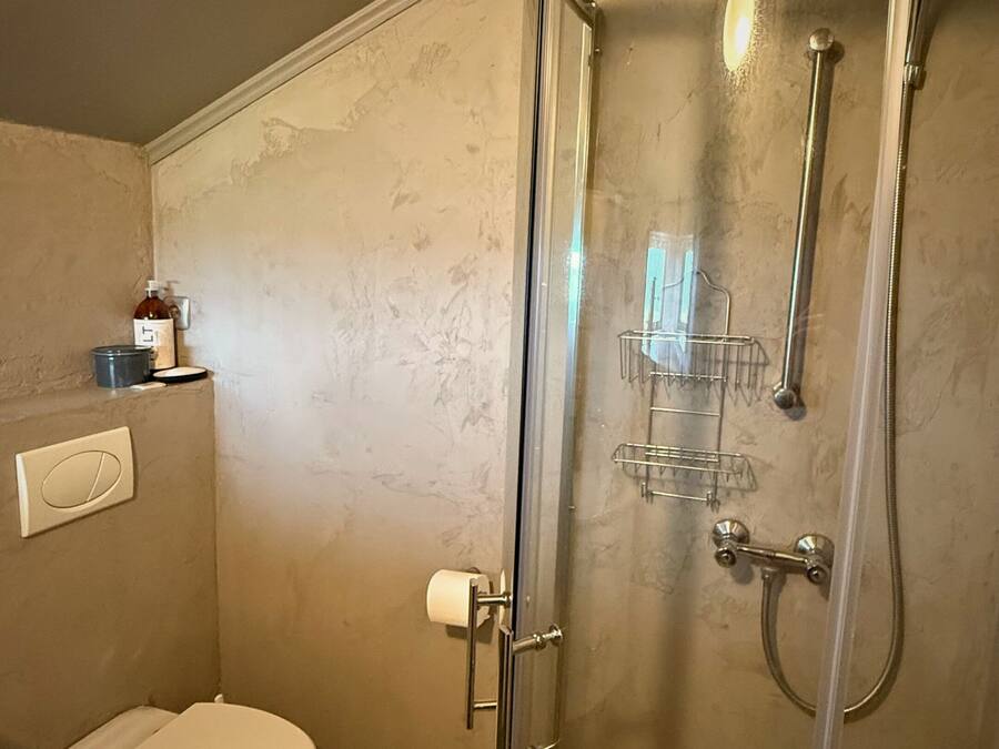 Un baño con inodoro, cabina de ducha y perchero.