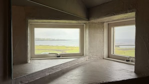 Quarto com duas janelas dando para a água e um espaço com grama.