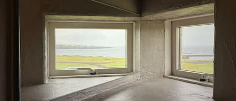 A room with two windows overlooking a body of water and a grassy area.