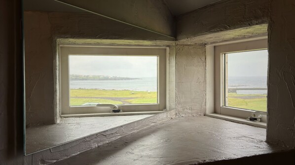 A room with two windows overlooking a body of water and a grassy area. - Snæfell Apartments (Hellissandur)