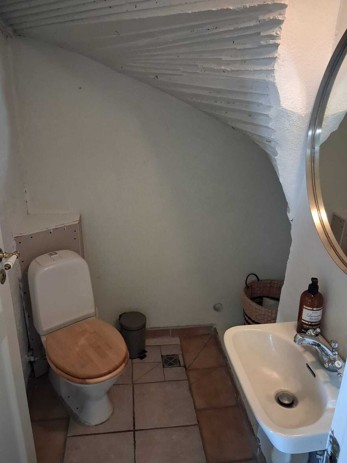 A small bathroom with a toilet, sink, and a mirror.