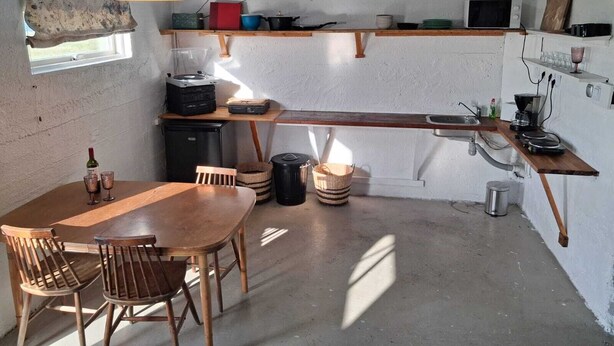 Uma cozinha compacta com uma mesa e cadeiras de madeira, micro-ondas e um refrigerador pequeno.