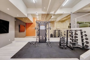 A gym with a squat rack, weight bench, and various dumbbells. - 110 Cook - Apartment in Old Quebec (Québec)