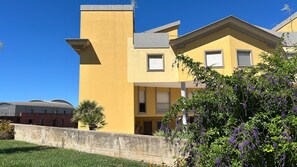 Un edificio amarillo de diseño moderno, con techo plano y un balcón.