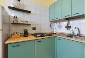 Una cocina con armarios color turquesa, una estufa a gas, un fregadero y diversos utensilios de cocina.