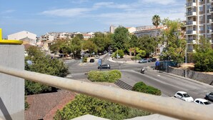 Uma rua urbana com edifícios, árvores e carros estacionados.