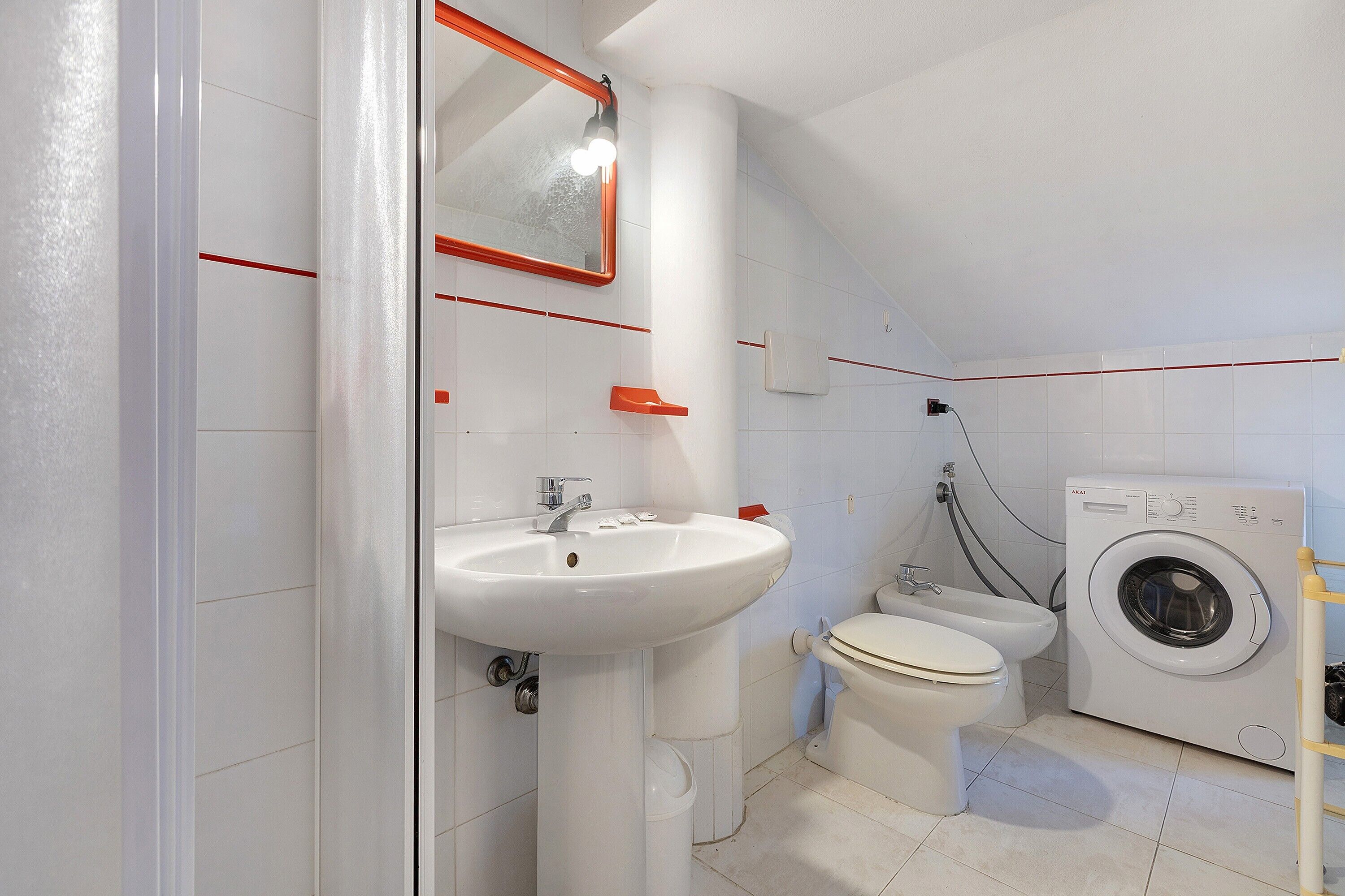 Une salle de bain équipée d’un lavabo, de toilettes et d’un lave-linge.