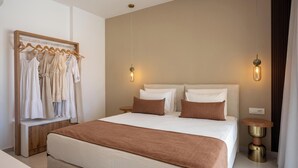 Ein Hotelzimmer mit einem großen Bett, zwei Nachttischen, einem Kleiderschrank und einer Kleiderstange.