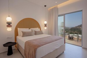 A modern bedroom with a large bed, a view of the countryside, and a balcony with outdoor furniture. - Sirocco Lux Villas (Agios Vasileios)