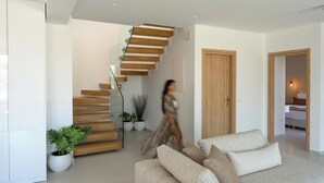 Ein modernes Interieur mit einer Treppe, einem Sofa und einer zur Schlafzimmertür führenden Öffnung.