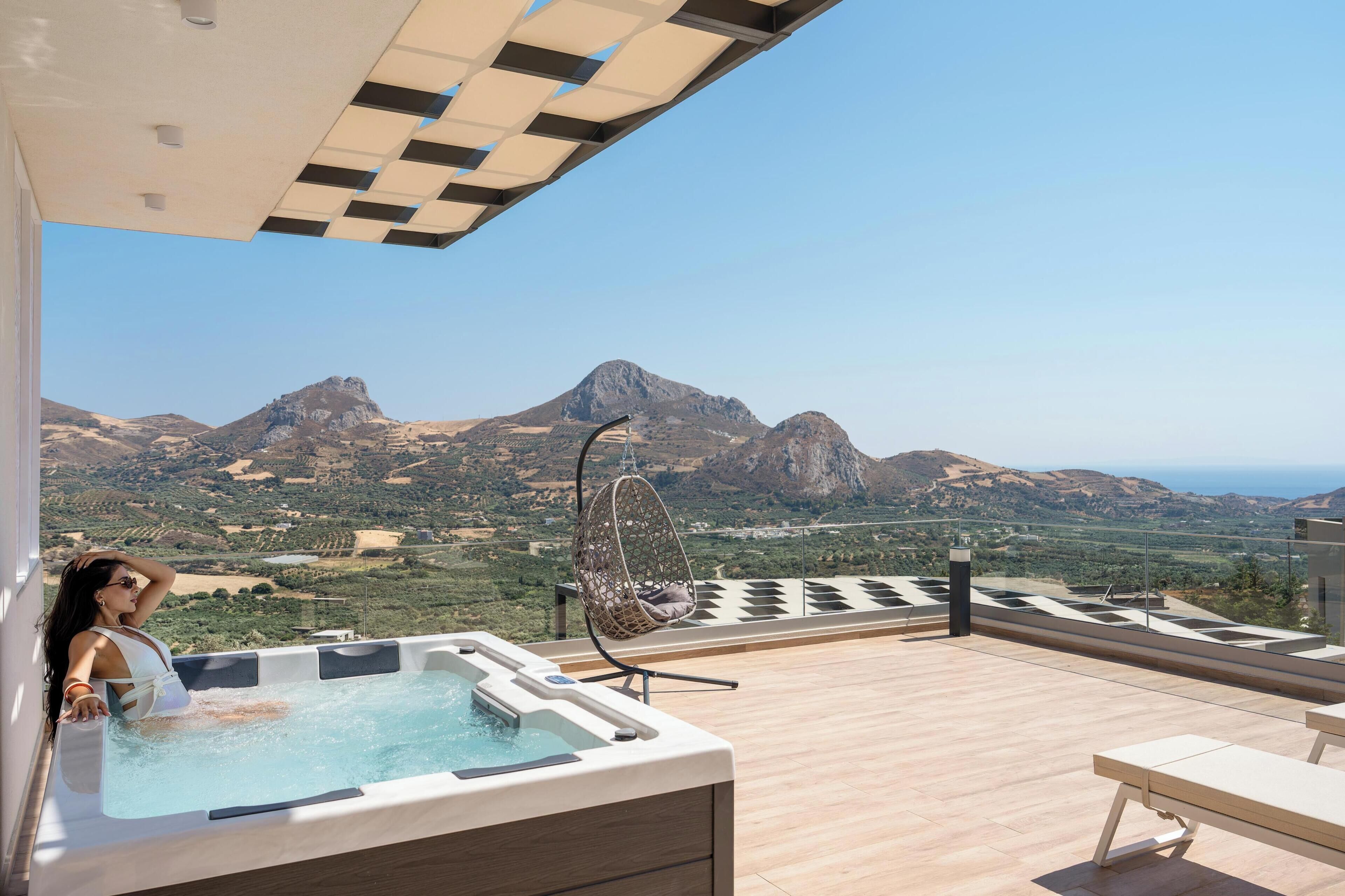 Una vasca idromassaggio su un pontile di legno con vista sulle montagne.