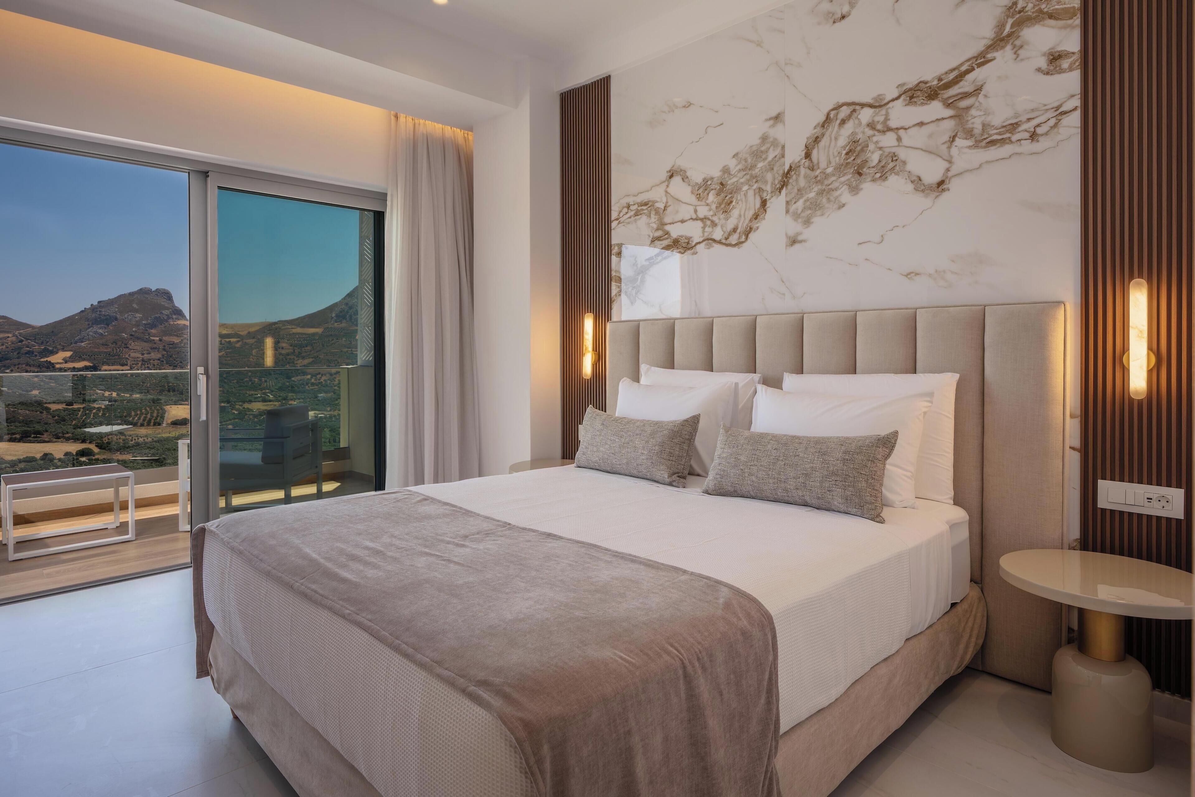 Un dormitorio con una cama grande, vistas al exterior y una pared de mármol.