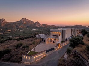 A modern villa with a spacious patio, a pool, and a view of the surrounding landscape. - Sirocco Lux Villas (Agios Vasileios)