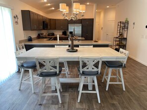 Cozinha moderna com ilha central, armários escuros e um lustre.
