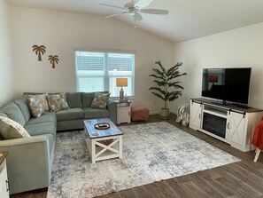 Ein Wohnzimmer mit einer Couch, einem Couchtisch, einem Fernseher und einer Zimmerpflanze.