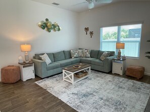 A living room with a sectional sofa, two side tables with lamps, a coffee table, and a patterned rug. - Live the Village Dream One Beautiful Day at a Time! (The Villages)
