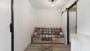 A narrow room with a patterned sofa, a small table, and a ceiling light fixture. - Apartment “Les Deux Alpes” with Mountain View, Balcony, and Wi-Fi (Les Deux Alpes)