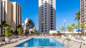 A swimming pool with sun loungers and tall buildings in the background. - Waikiki Banyan, Top Floor Oceanview Pool + Parking (Honolulu)