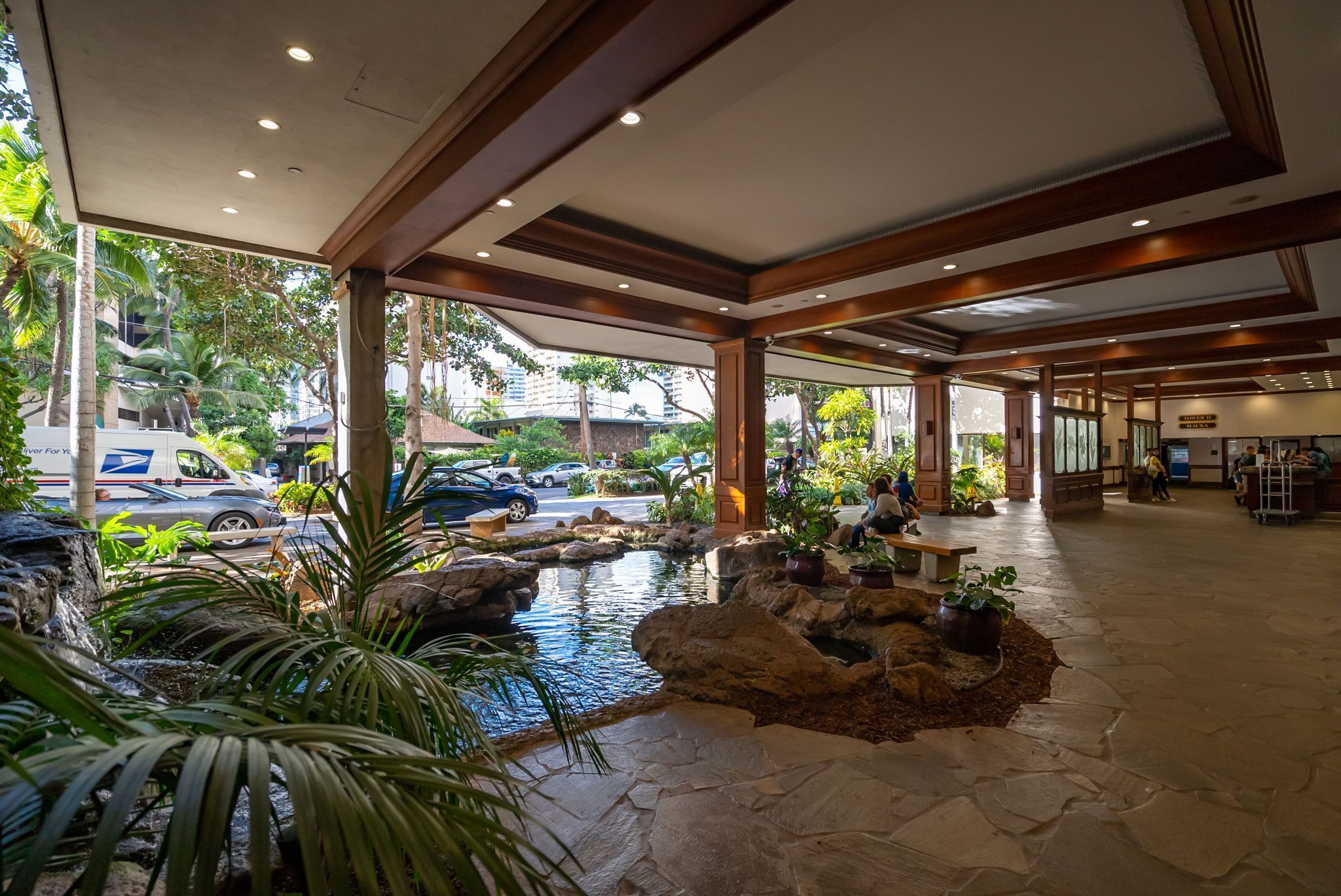 A hotel lobby with a water feature, seating area, and a view of the street.