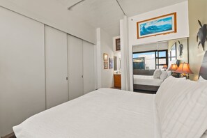 A hotel room with a large bed, a dresser, a mirror, and a painting on the wall. - Top-Floor Oceanview Waikiki Banyan| Pool Parking (Honolulu)