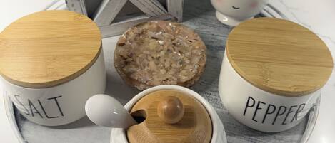 A tray with three containers labeled 'SALT,' 'PEPPER,' and a salt shaker, alongside a decorative plant and a rustic wooden box.