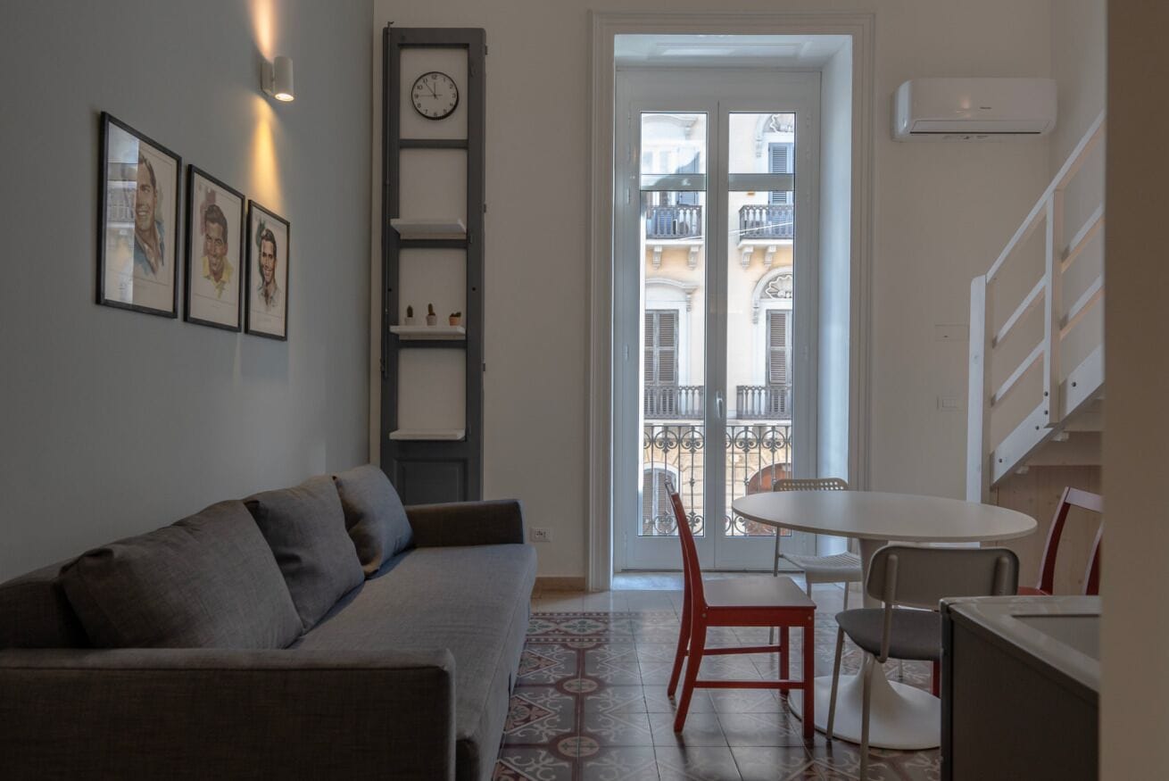 Un salon avec un canapé, une table à manger et des chaises, un escalier et une vue sur l’extérieur.