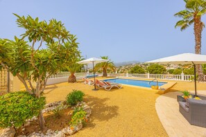 A pool area with lounge chairs, umbrellas, and a view of the landscape. - Villa Panoramick - Plusholidays (Calpe / Calp)
