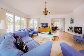 A modern living room with a sofa set, a television, a chandelier, and a fireplace. - Villa Panoramick - Plusholidays (Calpe / Calp)