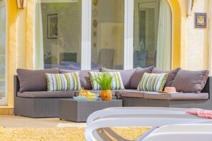 A sectional sofa with cushions and a small table with a plant and fruit. - Villa Panoramick - Plusholidays (Calpe / Calp)