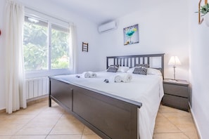 A bedroom with a bed, a bedside table, a lamp, and a window with curtains. - Villa Panoramick - Plusholidays (Calpe / Calp)