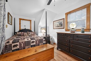 Ein Schlafzimmer mit einem Bett, einem Schminktisch, einem Nachttisch, einer Lampe und einem Fenster mit Jalousien.