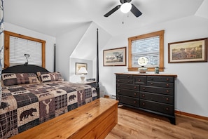 Ein Schlafzimmer mit Bett, Kommode und Bildern an den Wänden.