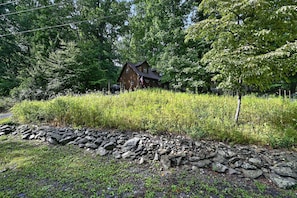 A rustic cabin surrounded by dense greenery and a stone wall. - Near Gettysburg | History, Trails & Dogs (Orrtanna)