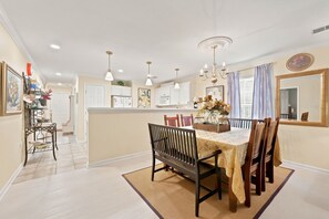 A dining area with a table set for four, a chandelier, and a view of the kitchen. - TB 71A First Floor True Blue Condo (Pawleys Island)