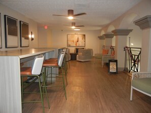 A bar area with stools and a counter, a seating area with chairs, and a ceiling fan. - Ocean front at Ocean reef resort, waterpark, beach (Myrtle Beach)