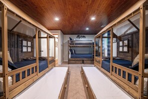 Ein Zimmer mit Etagenbetten, Holzbalken und einer Decke mit Einbuchtungslichtern.