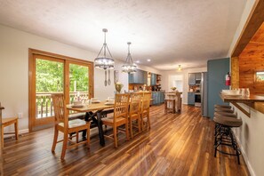 Eine geräumige Küche mit Holzboden, ein Essbereich mit Tisch und Stühlen sowie eine Bar mit Hockern.